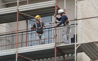 Due operai sui ponteggi di un palazzo in ristrutturazione, 18 aprile 2017 a Genova.
ANSA/LUCA ZENNARO